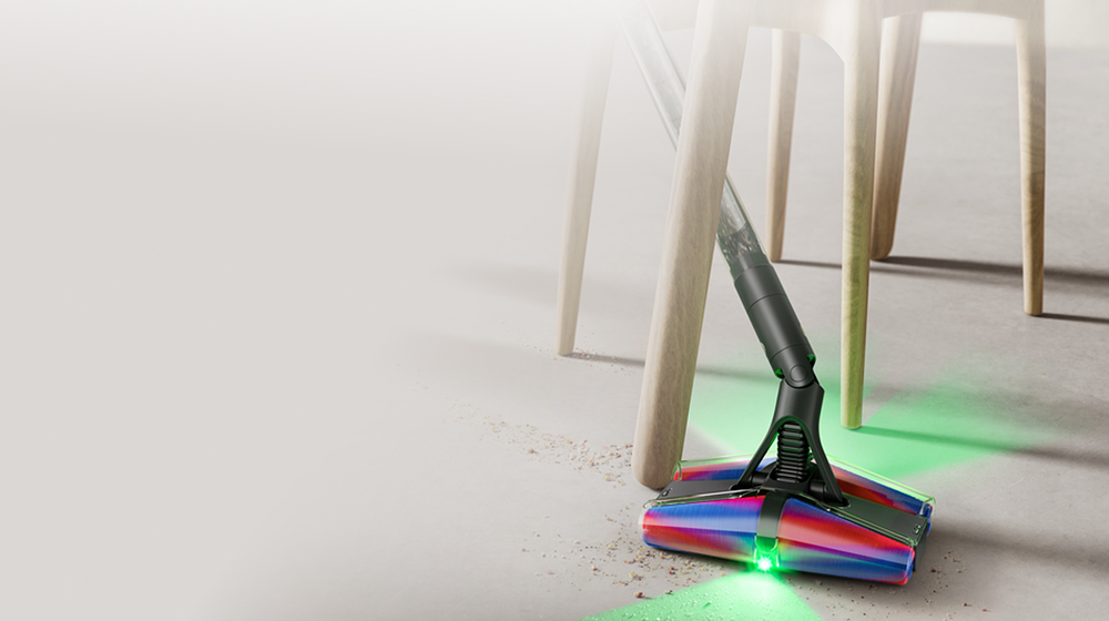 La aspiradora Dyson PencilVac Fluffycones se usa para limpiar debajo de un sofá bajo.